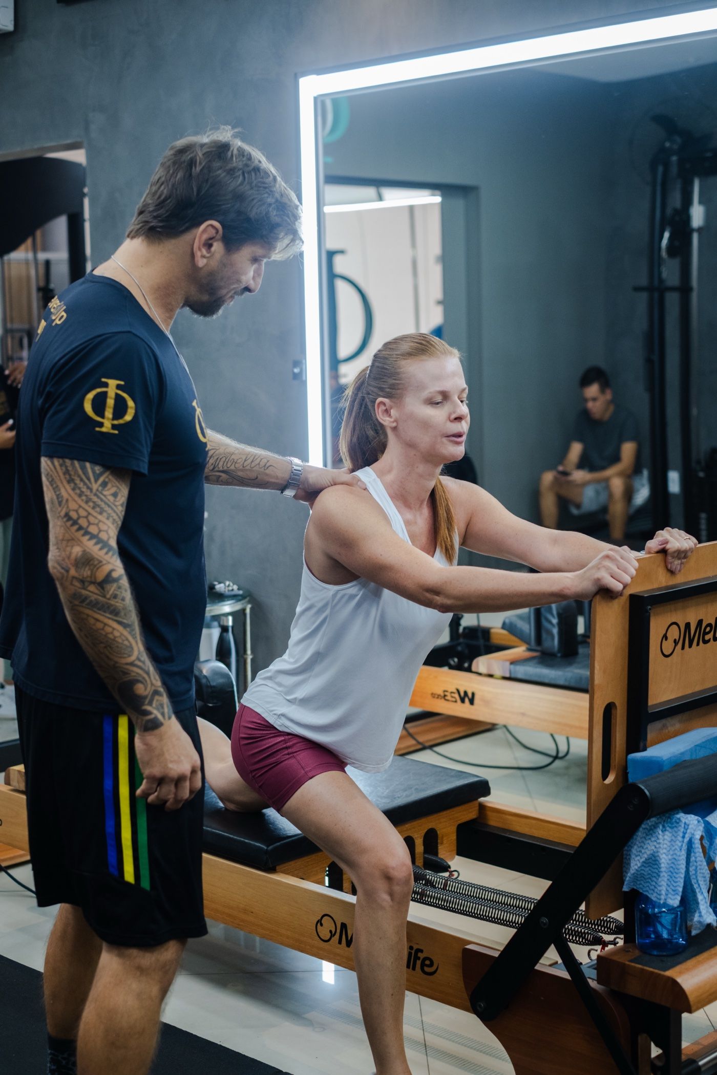 Aluna treinando no aparelho de Pilates com o professor